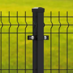 Fragment czarnego, metalowego ogrodzenia z panelem kratowym i słupkiem mocującym, na tle rozmytej zieleni.