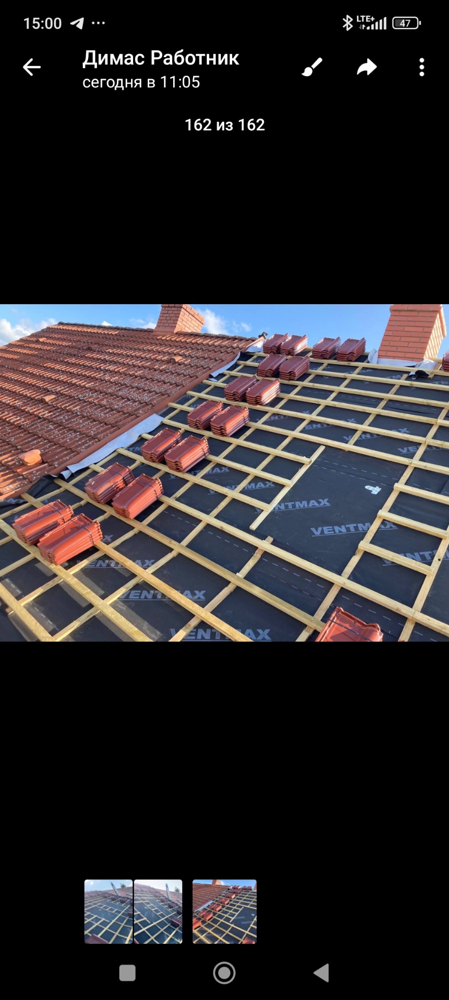 Układanie dachówki na łatach pokrytych membraną. Widok na dach z częściowo ułożonym pokryciem, kominem i błękitnym niebem. Prace dekarskie w toku.