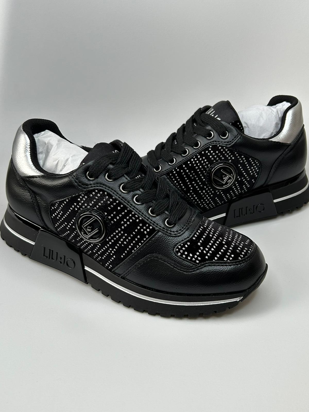 Para czarnych skórzanych sneakersów Liu Jo z srebrnymi akcentami i drobnymi błyszczącymi zdobieniami na cholewce, ustawionych na białym tle.