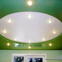 Roman Sokolov - Zielony sufit podwieszany z okrągłym, białym panelem centralnym i punktowym oświetleniem, widoczne okno w tle.