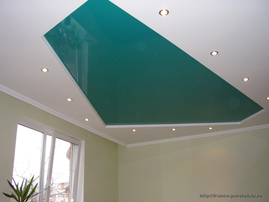 Sufit podwieszany z zielonym, lakierowanym panelem centralnym, otoczony białym sufitem z wbudowanymi punktowymi lampami LED. Widoczny fragment ściany w odcieniach beżu oraz okno.