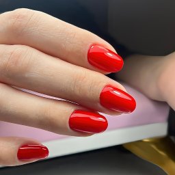 Pewność siebie w pigułce - czerwone paznokcie hybrydowe w eleganckim kształcie migdała! Intensywny kolor amarantowej czerwieni pokrywa wydłużone, zwężające się ku końcom paznokcie.