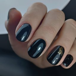 Elegancka klasyka w nowoczesnym wydaniu - czarny manicure hybrydowy ozdobiony złotymi akcentami. Głęboka czerń paznokci z lśniącym wykończeniem została uzupełniona o złotą folię