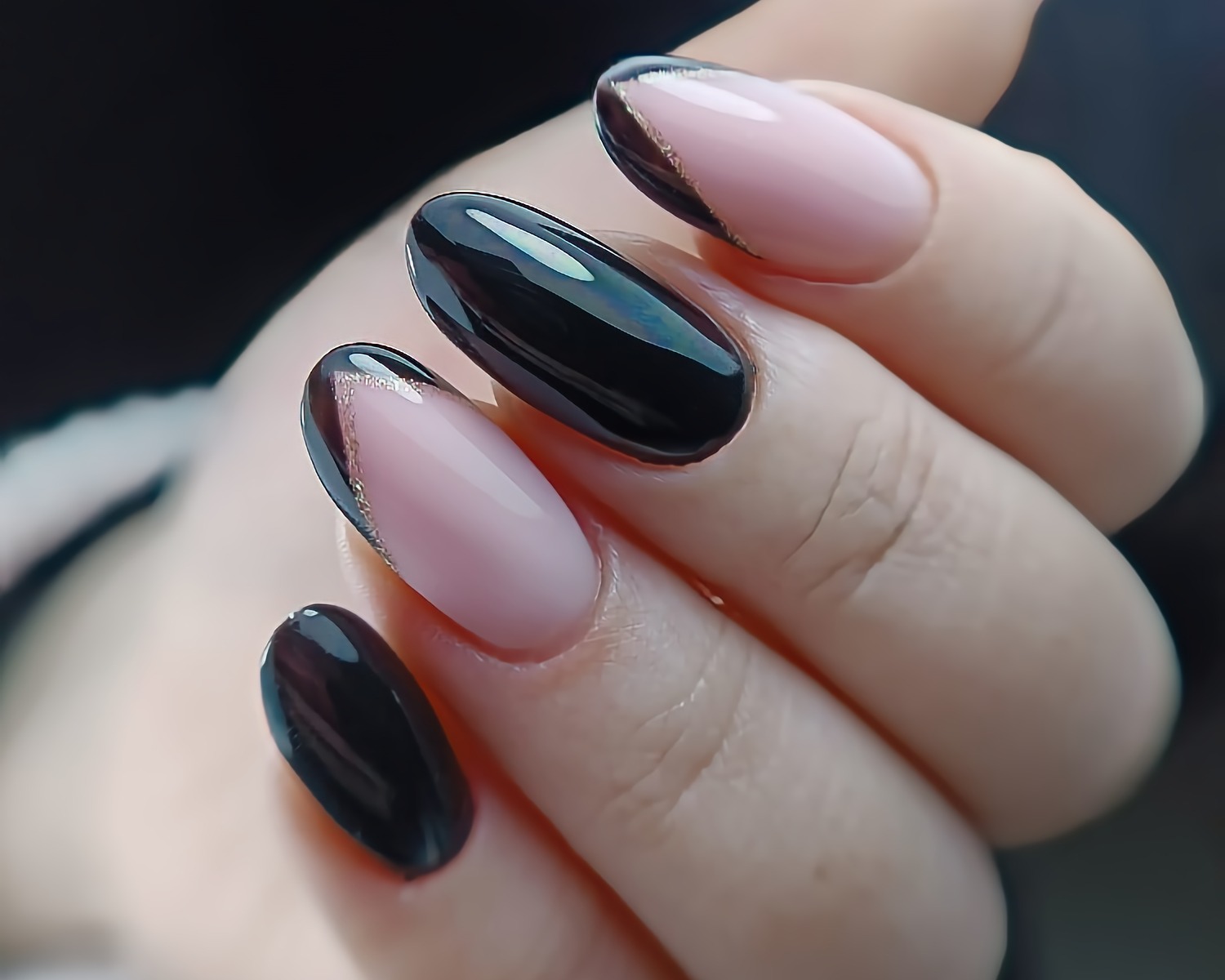 Elegancki manicure w Gdańsku: czarne, migdałowe paznokcie z podwójnym, czarno-złotym frenchem na tle delikatnej, pudrowej bazy.