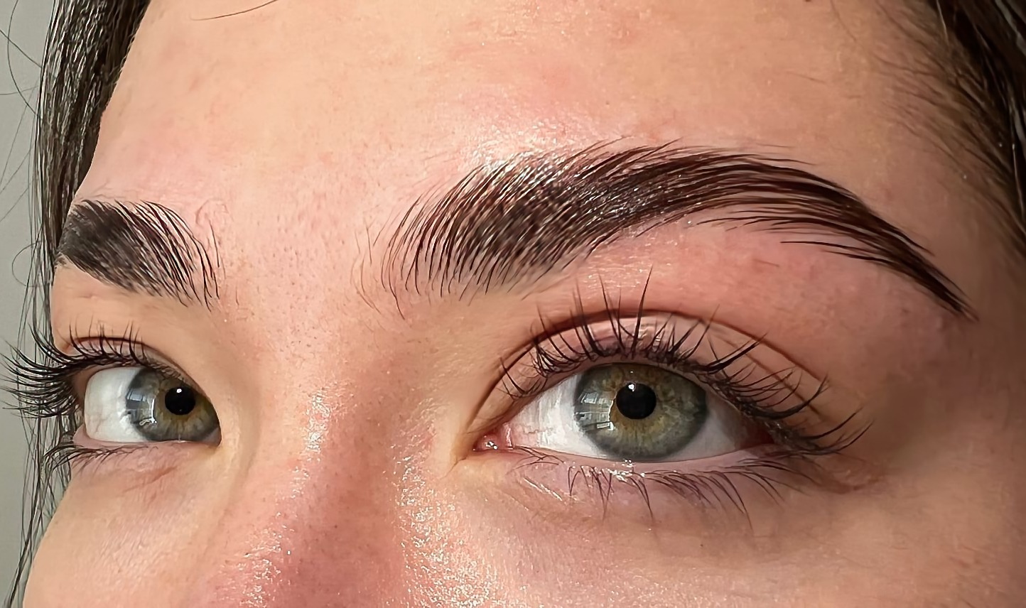 Zbliżenie na oko z wyraźnie podkreślonymi, laminowanymi brwiami i rzęsami, uwidoczniona struktura włosa, brwi gładko ułożone, rzęsy długie i podkręcone.