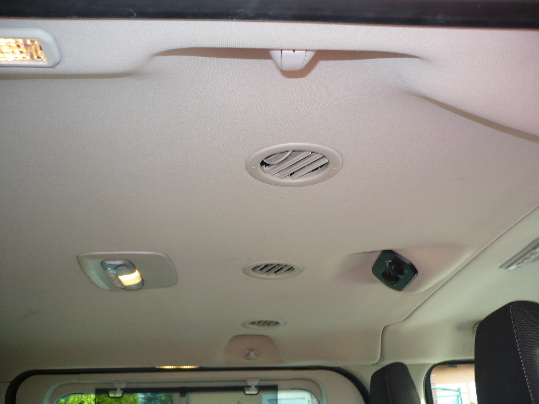 Wnętrze pojazdu z widoczną podsufitką, oświetleniem i nawiewami klimatyzacji, skierowane do góry.