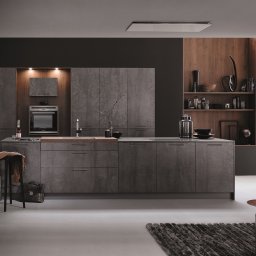 AGNIESZKA ĆWIERTNIAK-JANIA FORMAT HOME - Nowoczesna kuchnia z szarymi frontami imitującymi beton, drewnianym blatem wokół zlewu, oświetleniem LED i dekoracyjnymi półkami z akcesoriami.