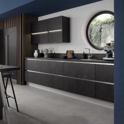 AGNIESZKA ĆWIERTNIAK-JANIA FORMAT HOME - Nowoczesna kuchnia z ciemnymi, matowymi frontami szafek, okrągłym oknem z widokiem na zieleń, drewnianą zabudową lodówki i wyspą z hokerem.