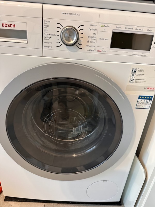 Pralka Bosch HomeProfessional z panelem sterowania pokazującym różne programy prania, widoczne logo Bosch na drzwiczkach i obudowie, certyfikat ECARF Quality Tested.