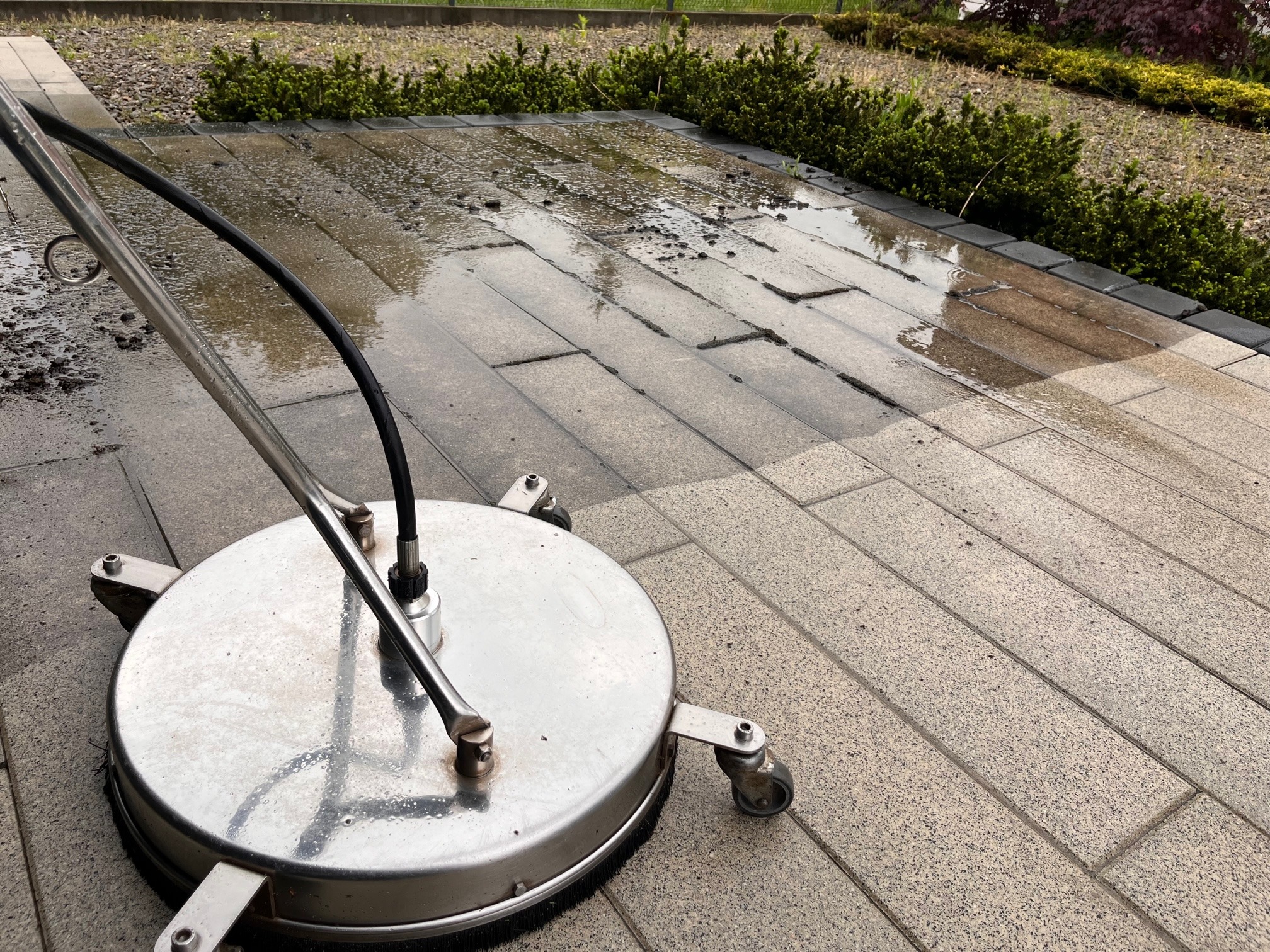 Czyszczenie kostki brukowej w Tarnowie za pomocą profesjonalnej myjki ciśnieniowej z okrągłą dyszą, widoczny efekt przed i po umyciu.