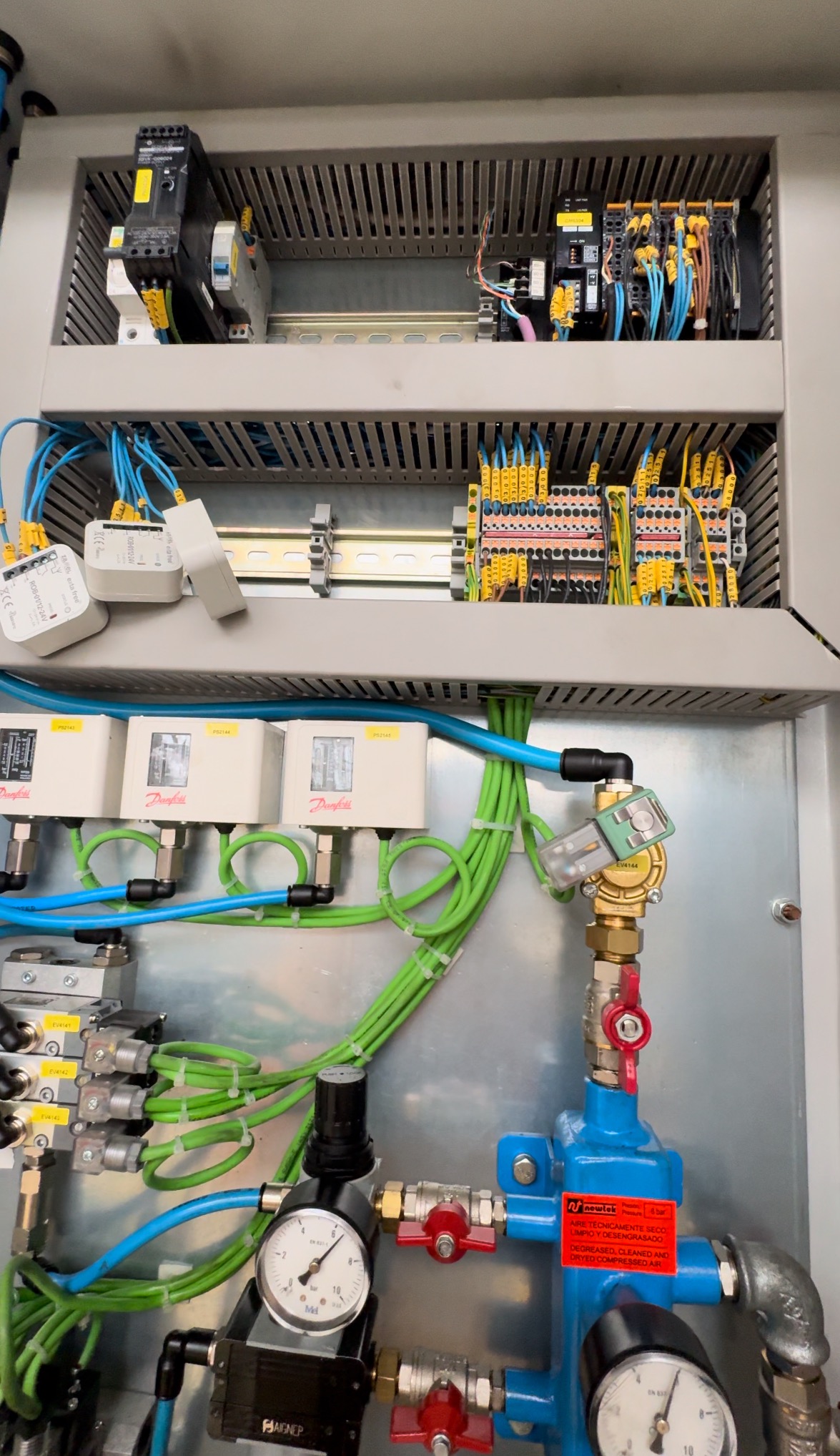 Rozdzielnica elektryczna z widocznymi elementami automatyki przemysłowej, w tym sterowniki, czujniki Danfoss, zawory elektromagnetyczne, manometry i liczne przewody w kolorach niebieskim i zielonym.