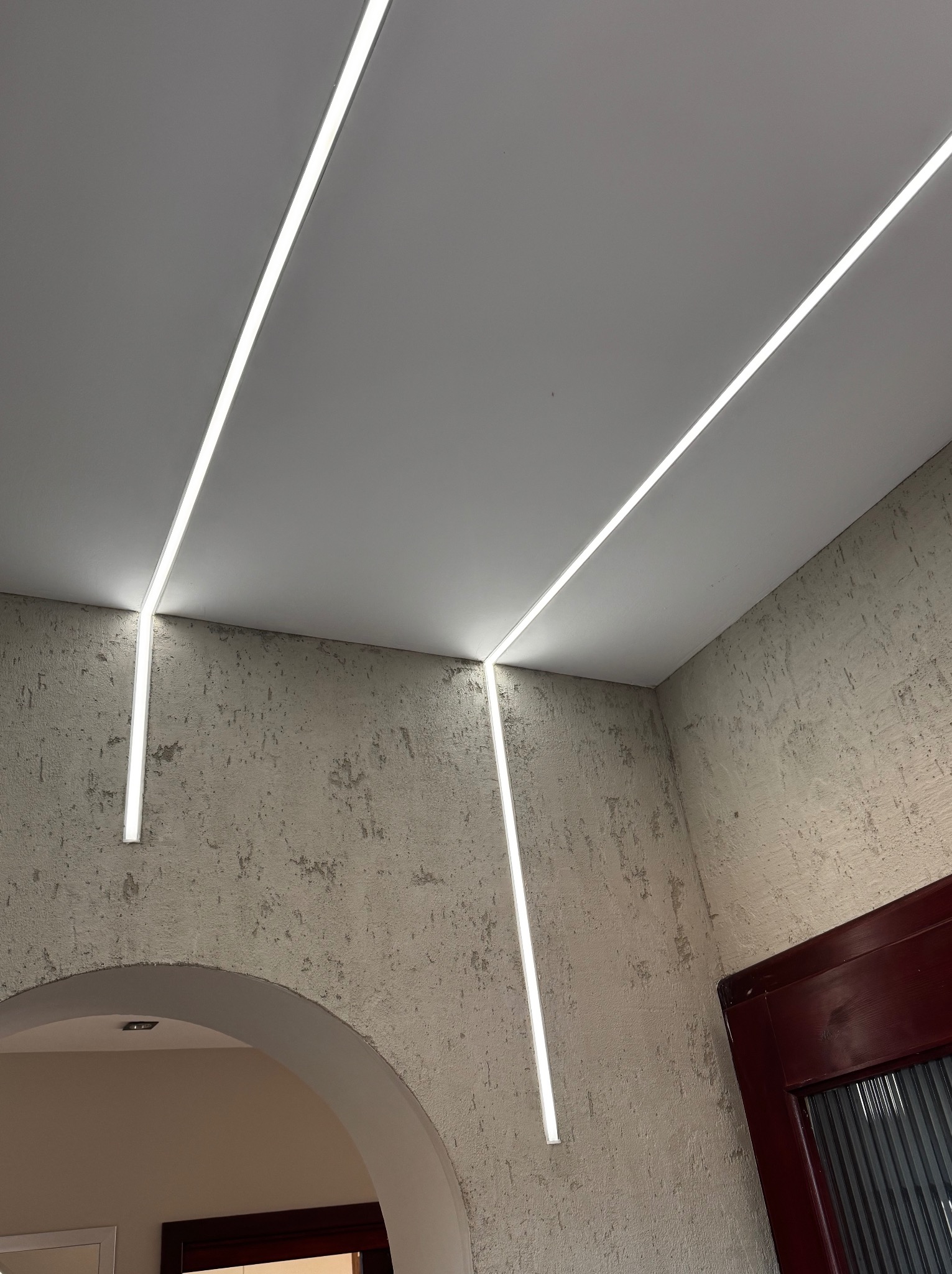 Nowoczesne oświetlenie LED wpuszczone w sufit i ściany o fakturze betonu, tworzące minimalistyczny design wnętrza.