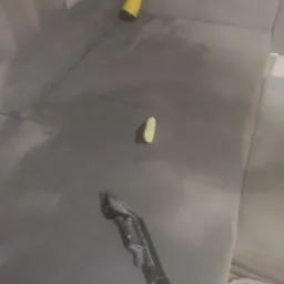 Szara kanapa z widocznymi plamami, w trakcie czyszczenia: odkurzacz piorący z dyszą, ż&oacute;łty spryskiwacz i szczotka do tapicerki.