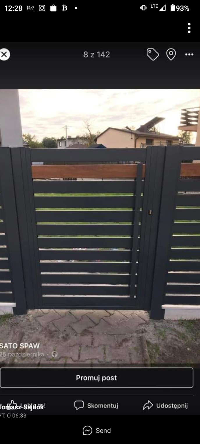 Nowoczesna brama wjazdowa z poziomych, grafitowych paneli, z drewnianym akcentem u góry, na tle domu jednorodzinnego i brukowanej ścieżki.