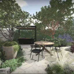 Aranżacja ogrodu z okrągłym stołem i czarnymi krzesłami na kamiennej nawierzchni. W tle roślinność, drzewa i zabudowa grillowa.