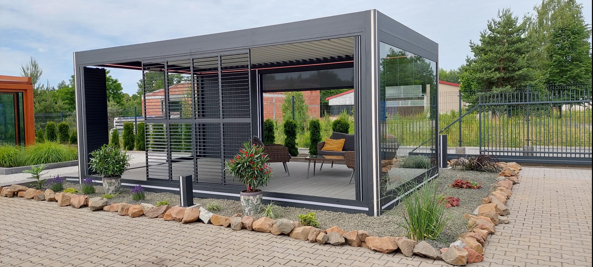 Nowoczesna pergola aluminiowa z przesuwnymi żaluzjami i szklanymi panelami w Katowicach. Elementy oświetleniowe podkreślają elegancję konstrukcji.
