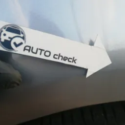 Pomiar grubości lakieru na srebrnym samochodzie za pomocą miernika 'AUTO check'.