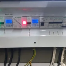 Rozdzielnica elektryczna z licznikami zużycia energii (sieć i PV), zabezpieczeniami r&oacute;żnicowoprądowymi i nadprądowymi, opisana etykietami dla r&oacute;żnych obwod&oacute;w (Boiler, Garaz, Piwnica, Strych...