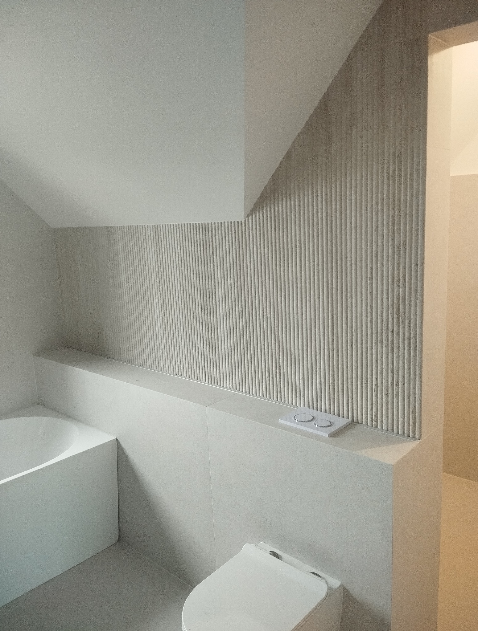 Minimalistyczna łazienka w odcieniach szarości z wanną, toaletą i ścianą z dekoracyjnymi, pionowymi żłobieniami. Uwagę przykuwa spójność kolorystyczna i nowoczesny design.