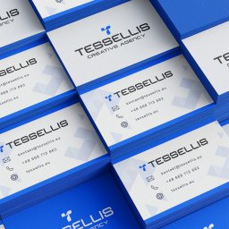 Nouva Atelier - Marta Lińska - Stos wizytówek z niebieskimi krawędziami, ułożonych pod kątem. Widoczne dane kontaktowe i logo firmy Tessellis Creative Agency. Minimalistyczny design, ostre światło.