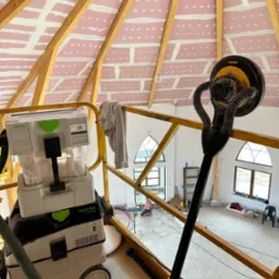 Sufit z płyt kartonowo-gipsowych na drewnianej konstrukcji, w trakcie szpachlowania łączeń, widoczny szlifierka do gipsu z odkurzaczem przemysłowym Festool, oraz fragment rusztowania.