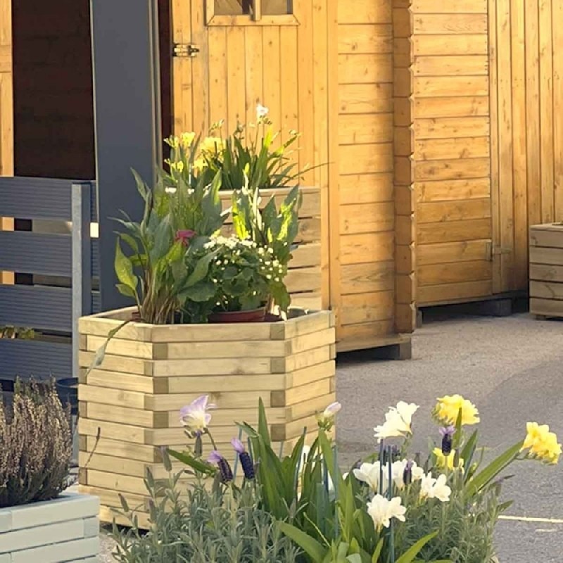 Drewniane donice z kwiatami przed domem szkieletowym w Jeleniej Górze; widoczna faktura drewna i różnorodność zasadzonych roślin.