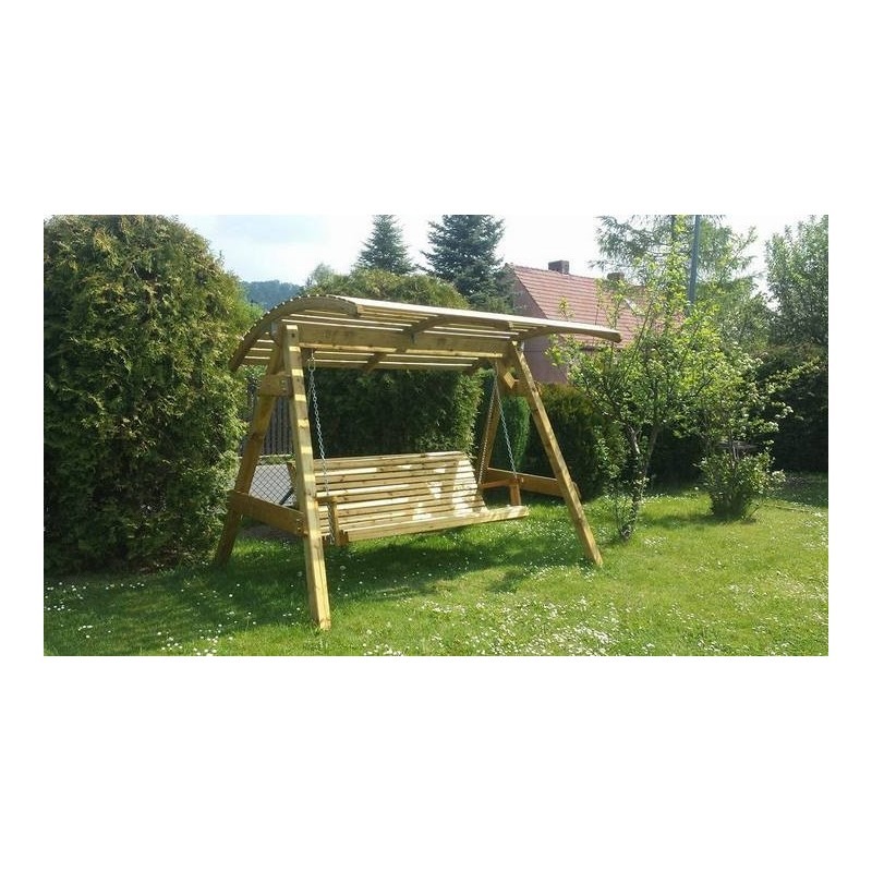 Drewniana huśtawka ogrodowa z zadaszeniem, zawieszona na łańcuchach, umieszczona na trawniku z kwitnącymi stokrotkami, w tle krzewy i drzewa.