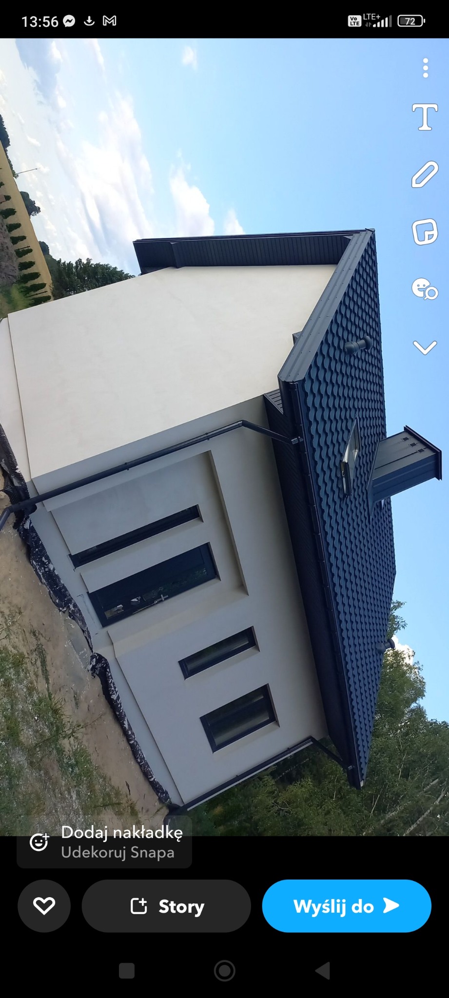 Nowoczesny dom z ciemną dachówką i jasną elewacją, widok z dołu, z widocznymi oknami i elementami wykończeniowymi.