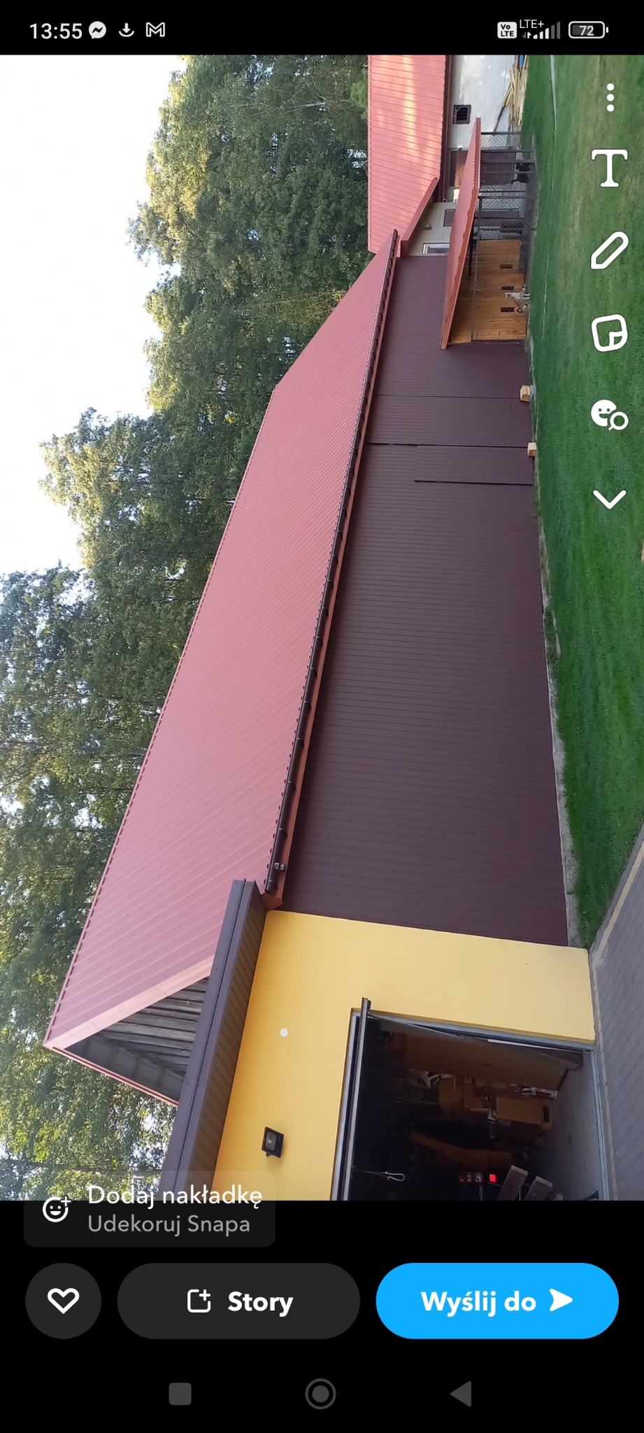 Widok z góry na budynek z dachem z blachy w odcieniach czerwieni i brązu, z żółtą ścianą garażu i zielonym trawnikiem w tle.