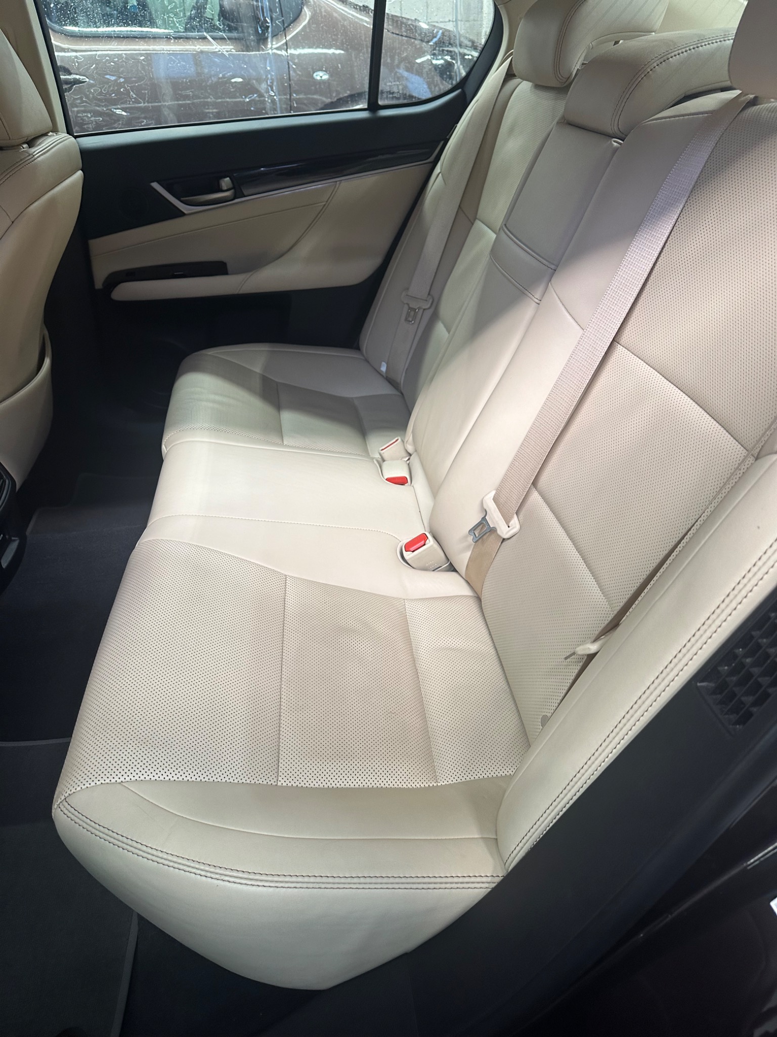 Jasna skórzana tylna kanapa samochodu po czyszczeniu, widoczne detale perforacji i szwy.