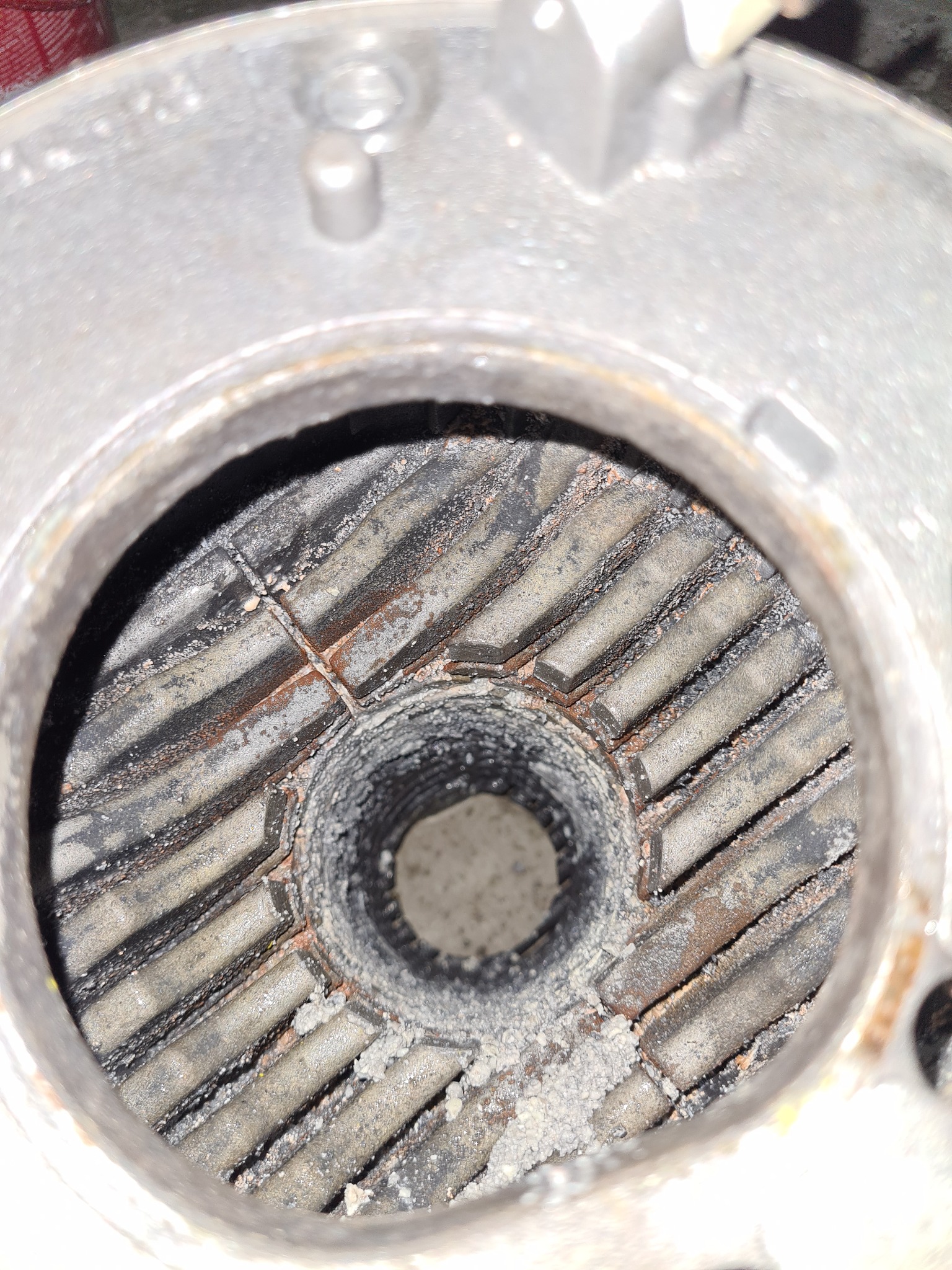 Wnętrze skorodowanego wymiennika ciepła z widocznym nagarem i osadami, sfotografowane z bliska pod kątem.