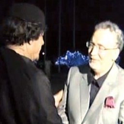 Mateos Acess Financial Inter Country - Dwóch mężczyzn w garniturach rozmawia ze sobą na tle oświetlonych dekoracji zewnętrznych.