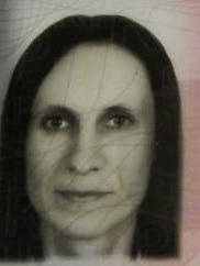 Portret kobiety z ciemnymi włosami, skierowanej twarzą w stronę obiektywu, na tle z delikatnymi wzorami.