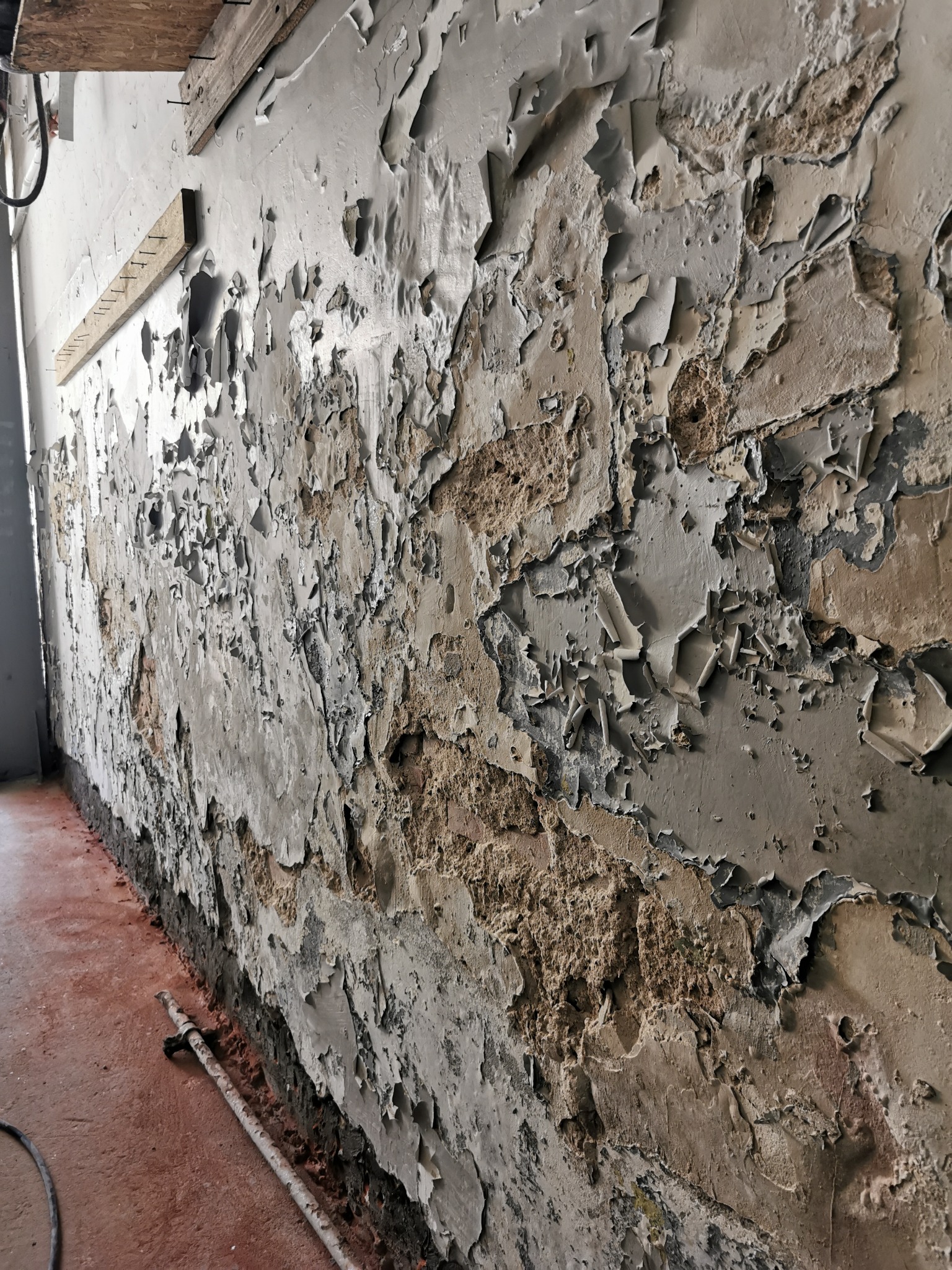 Ściana w Gdańsku z odpadającym tynkiem i widocznymi śladami zawilgocenia, przygotowana do osuszania.