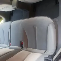 Wnętrze samochodu: tylna kanapa z jasną, szarą tapicerką z widocznymi mocowaniami ISOFIX oraz pasami bezpieczeństwa