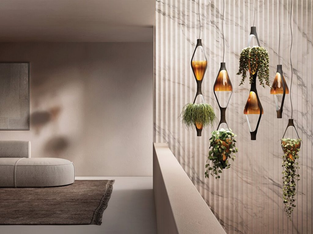 Nowoczesne lampy wiszące z roślinami w szklanych kloszach, marmurowa ściana w tle, minimalistyczny salon z szarym dywanem i pufą.
