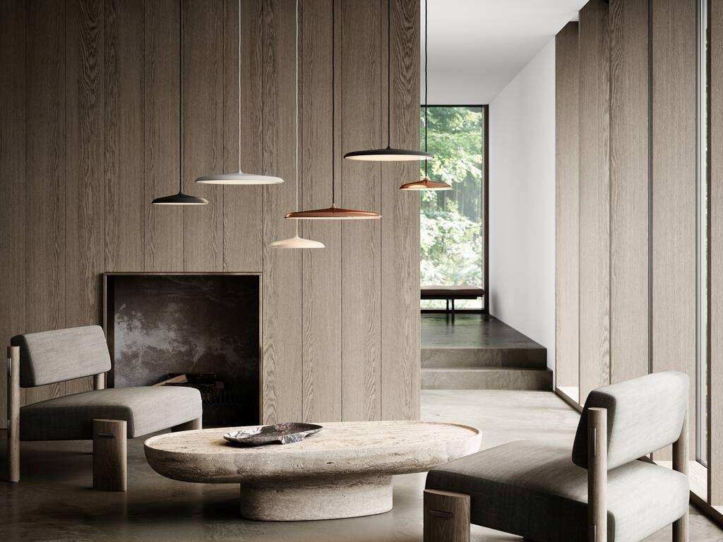 Minimalistyczny salon z drewnianymi panelami ściennymi, kamiennym stolikiem kawowym i wiszącymi lampami dyskowymi w różnych kolorach, z widokiem na zieleń za oknem.