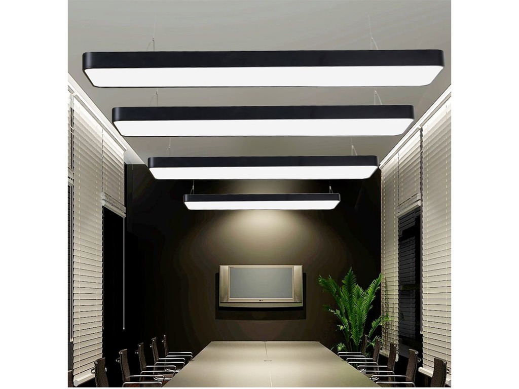 Nowoczesna sala konferencyjna z długim stołem, krzesłami i czterema podwieszanymi, prostokątnymi lampami LED o czarnej obudowie, z widocznym ekranem na ścianie i rośliną doniczkową.