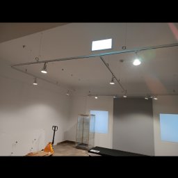 Piotr Słomka - Wnętrze sklepu w trakcie przygotowań do otwarcia, widoczne szyny oświetleniowe pod sufitem, paleciak i gablota wystawowa