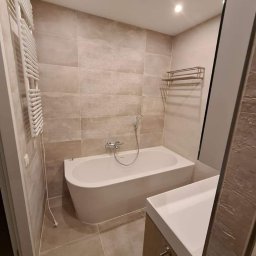 Paweł Gnida - Nowoczesna łazienka w beżowych odcieniach z wolnostojącą wanną, umywalką nablatową i grzejnikiem drabinkowym.