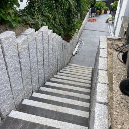 BS BudSerwis - Schody zewnętrzne z kostki brukowej w odcieniach szarości, z granitowymi obrzeżami, prowadzące w dół. Widok z góry na ukończony projekt.