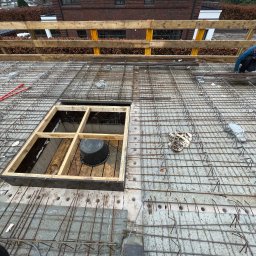 BS BudSerwis - Zbrojenie stropu z otworem na schody w Olsztynie. Widoczne pręty, betonowe podkładki dystansowe i pracownik przy pracy. Realizacja z góry.