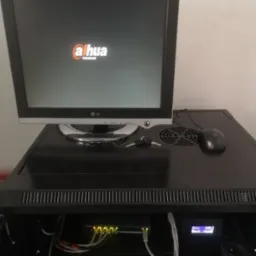 Monitor z logo Dahua na szafie rack z przełącznikiem sieciowym, myszką i kluczem na górze