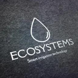 Logo firmy z nazwą ECOSYSTEMS i symbolem kropli wody, z dopiskiem 'Smart irrigation technology', na ciemnoszarym teksturowanym tle.
