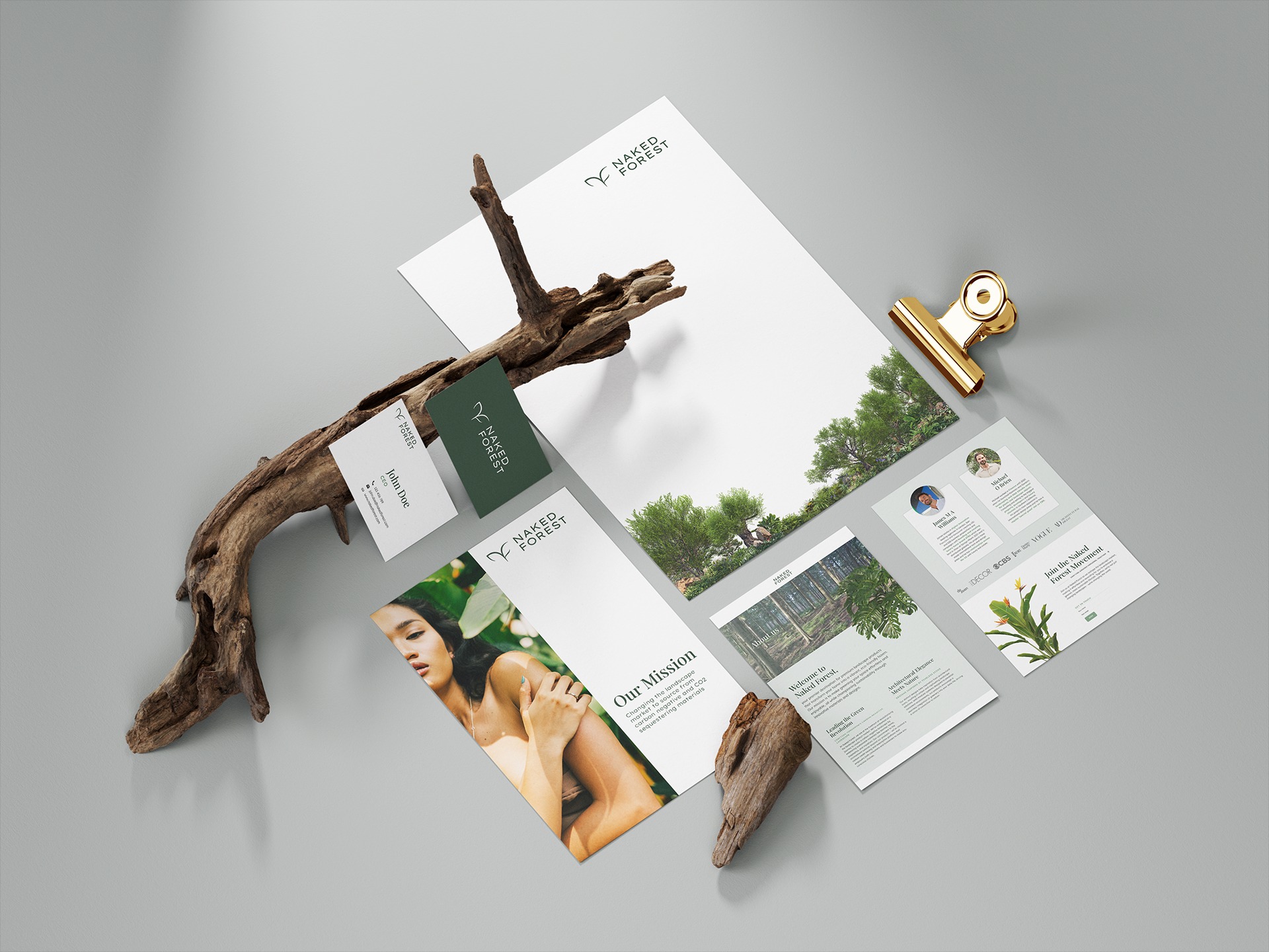 Zestaw materiałów firmowych z logo Naked Forest: wizytówka, papier firmowy, broszury informacyjne z misją firmy, ułożone na szarym tle z dekoracyjnymi elementami z drewna.