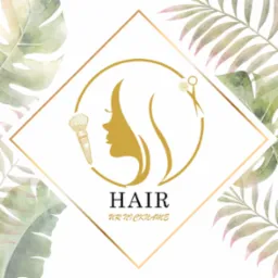 Złote logo salonu fryzjerskiego z profilem kobiety, pędzlem do makijażu i nożyczkami na tle akwarelowych liści palmowych w ramie.