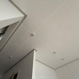 CleverHouse Paweł Piotrowski - Minimalistyczne wnętrze z zamontowanym oświetleniem punktowym na suficie, wyznaczonymi liniami laserowymi, ukazujące precyzję montażu.