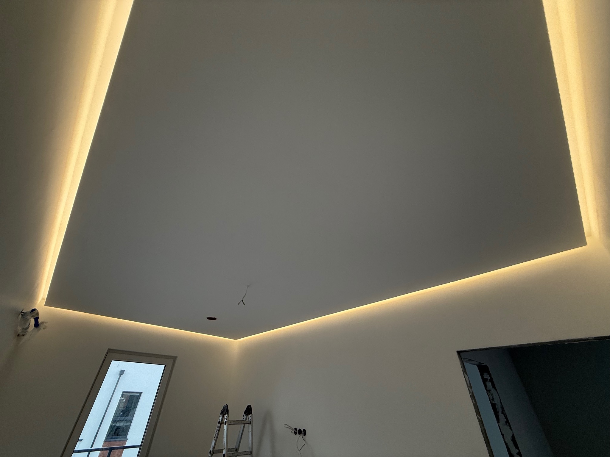 Nowoczesne oświetlenie sufitowe LED w kształcie kwadratu, z drabinką w rogu pokoju. Minimalistyczny design, ciepłe światło.