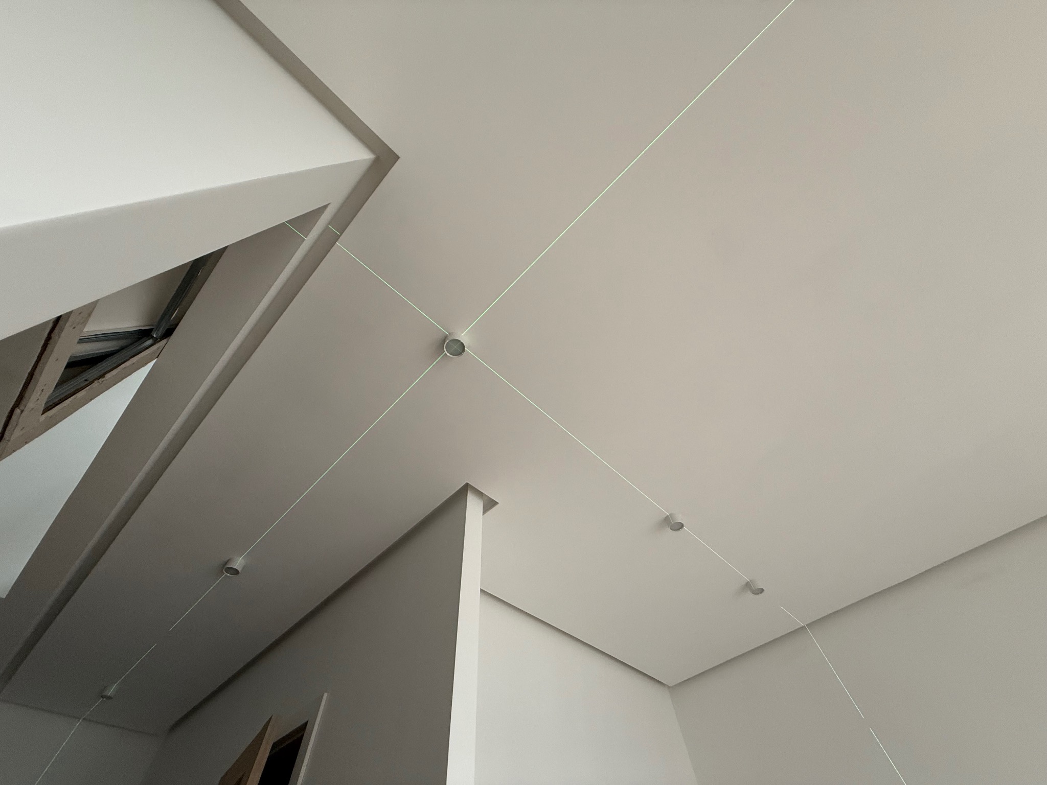 Minimalistyczne wnętrze z zamontowanym oświetleniem punktowym na suficie, wyznaczonymi liniami laserowymi, ukazujące precyzję montażu.