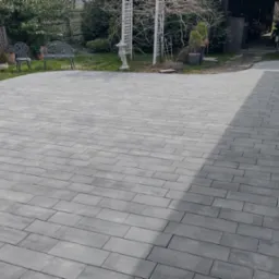 Ułożona szara kostka brukowa na podwórku w Częstochowie, widoczny fragment ogrodu z ozdobną ławeczką i altanką.